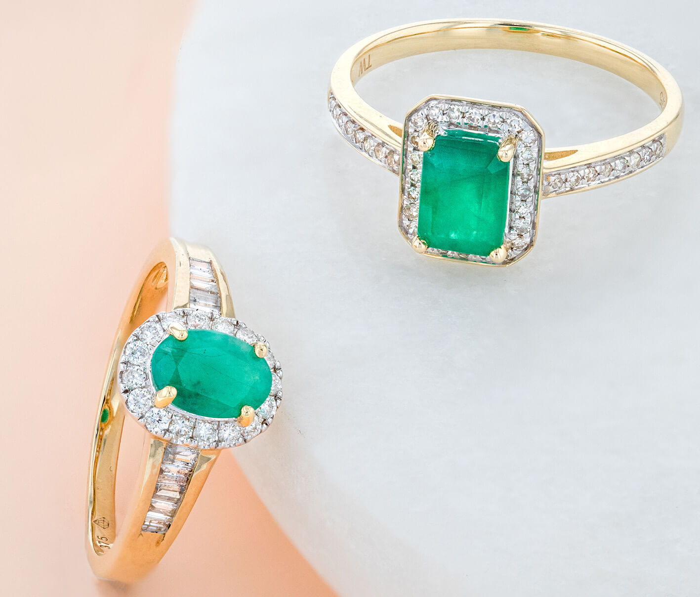 Best Emerald Engagement Rings. Two emerald gold rings lying flat, and set with diamonds. 