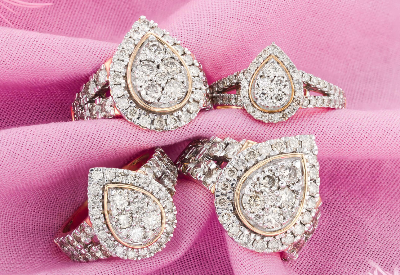 A Look at Our Best Pear Engagement Rings: Four pear diamond rings sitting on pink material