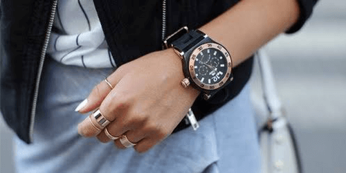 a woman wearing one of the best masculine watches for ladies on her left wrist. the watch is black with rose gold finishes