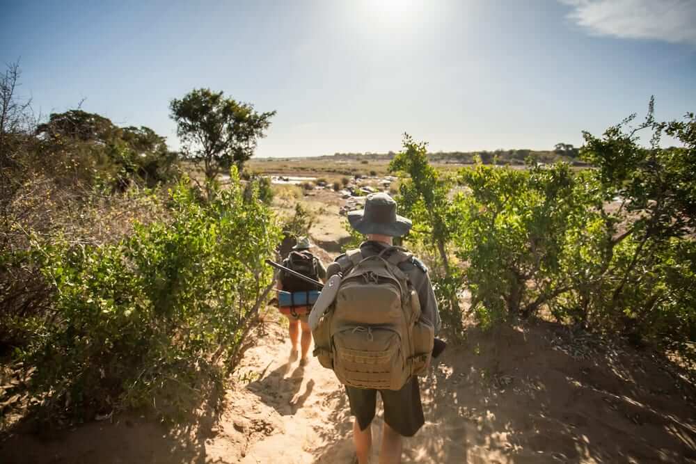 A man and woman walking on sarai with backpacks and camping gear