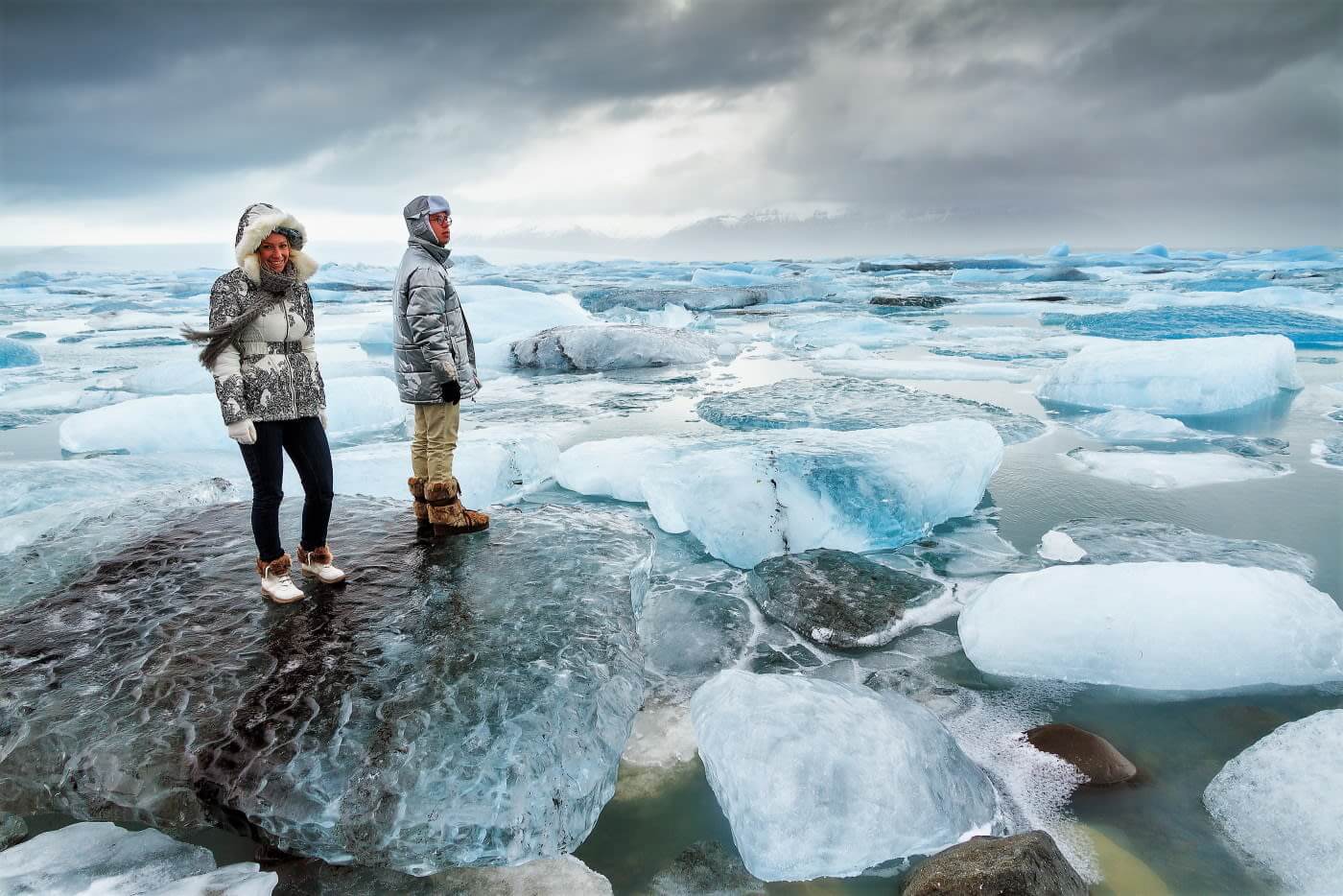 A couple standing on icebergs in Iceland