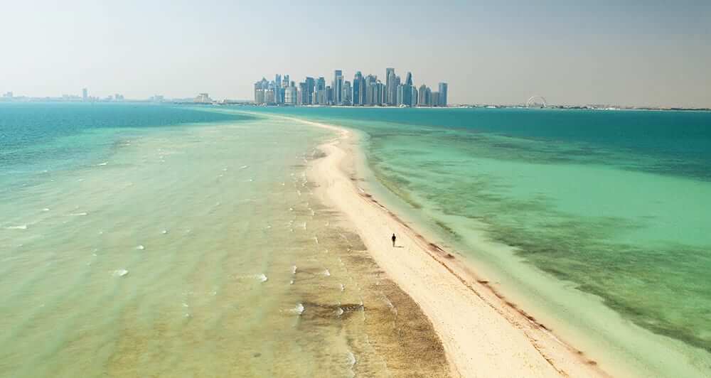 Beach path and ocean with view of the Qatar skyline
